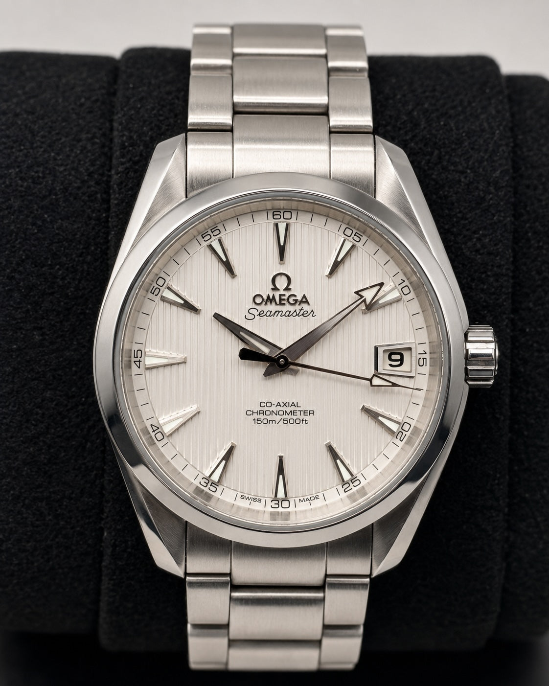 Omega Seamaster Co-Axial Chronometer watch with a silver stainless steel bracelet and a white dial, displayed on a black watch stand.