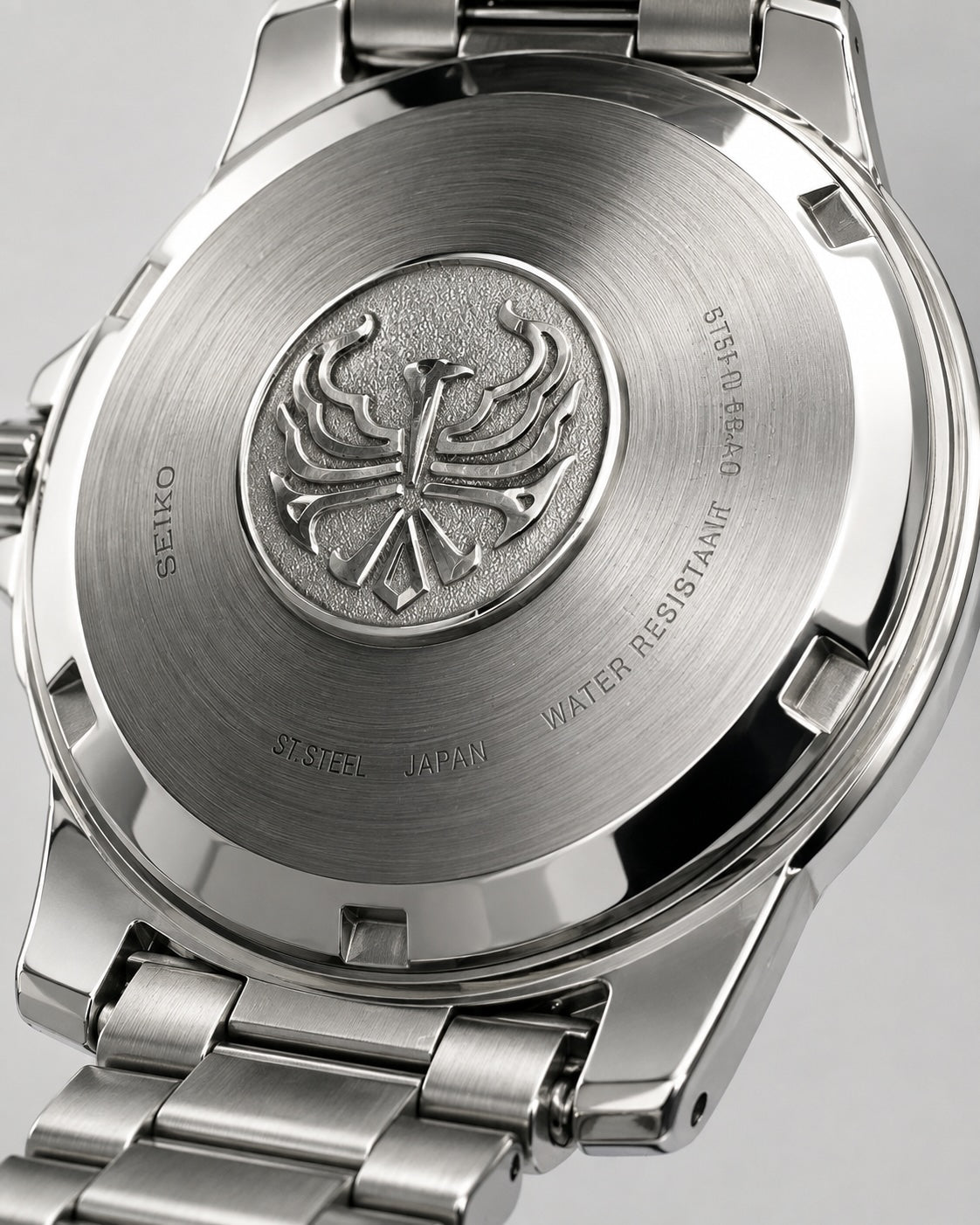 Close-up of the brushed stainless steel case back of a Seiko watch, showing the engraved Seiko logo and water resistance text, with part of the metal bracelet visible.