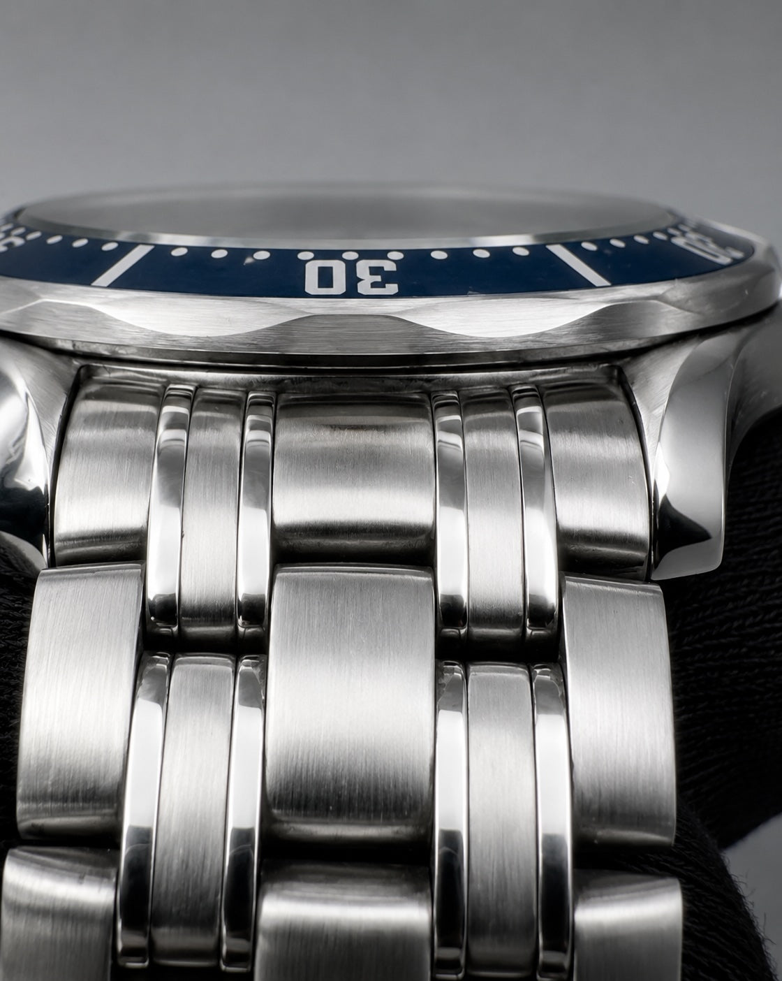 Close-up of a stainless steel bracelet watch with a blue dial bezel and white numerals.