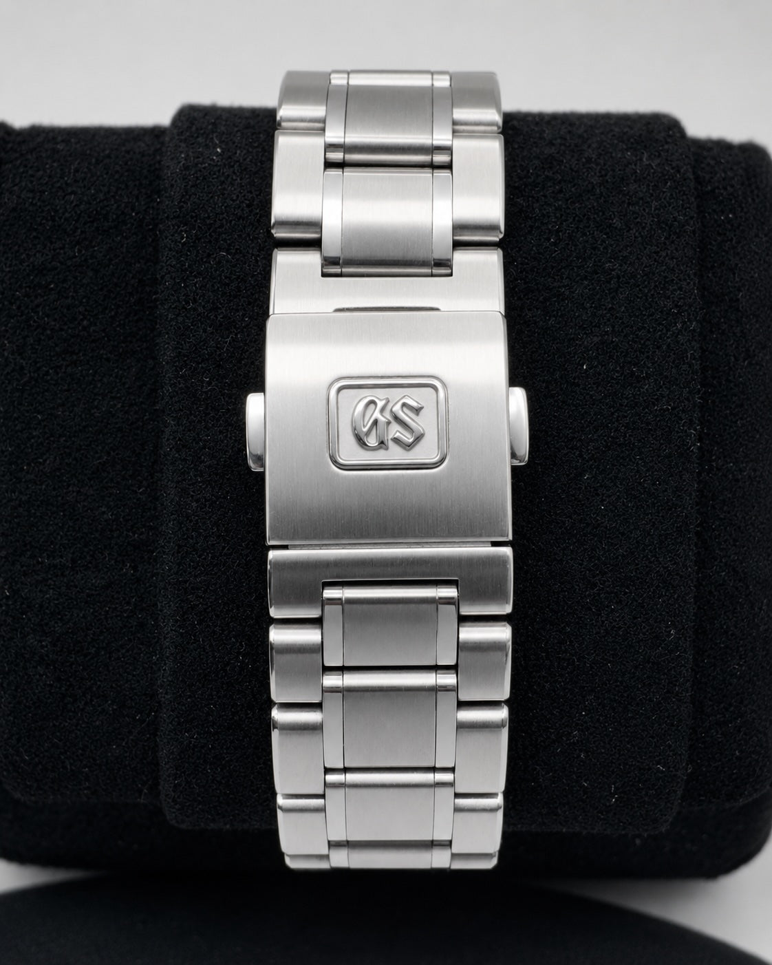 A stainless steel link bracelet watch band with a brushed and polished finish, featuring an engraved 'KS' logo on the clasp, displayed on a black velvet watch stand.