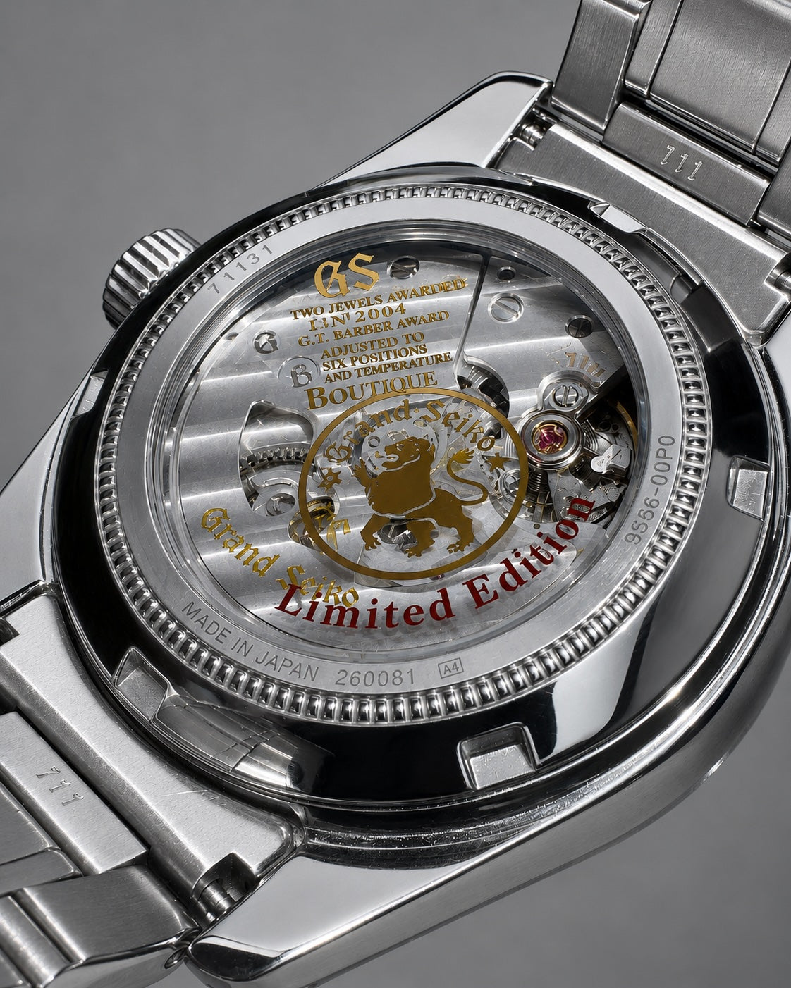 Close-up of the back of a stainless steel wristwatch with a transparent case, showing the inner movement and a gold-and-red lion emblem. Visible text includes 'GS', 'Grand Seiko', 'Limited Edition', and 'Made in Japan'.