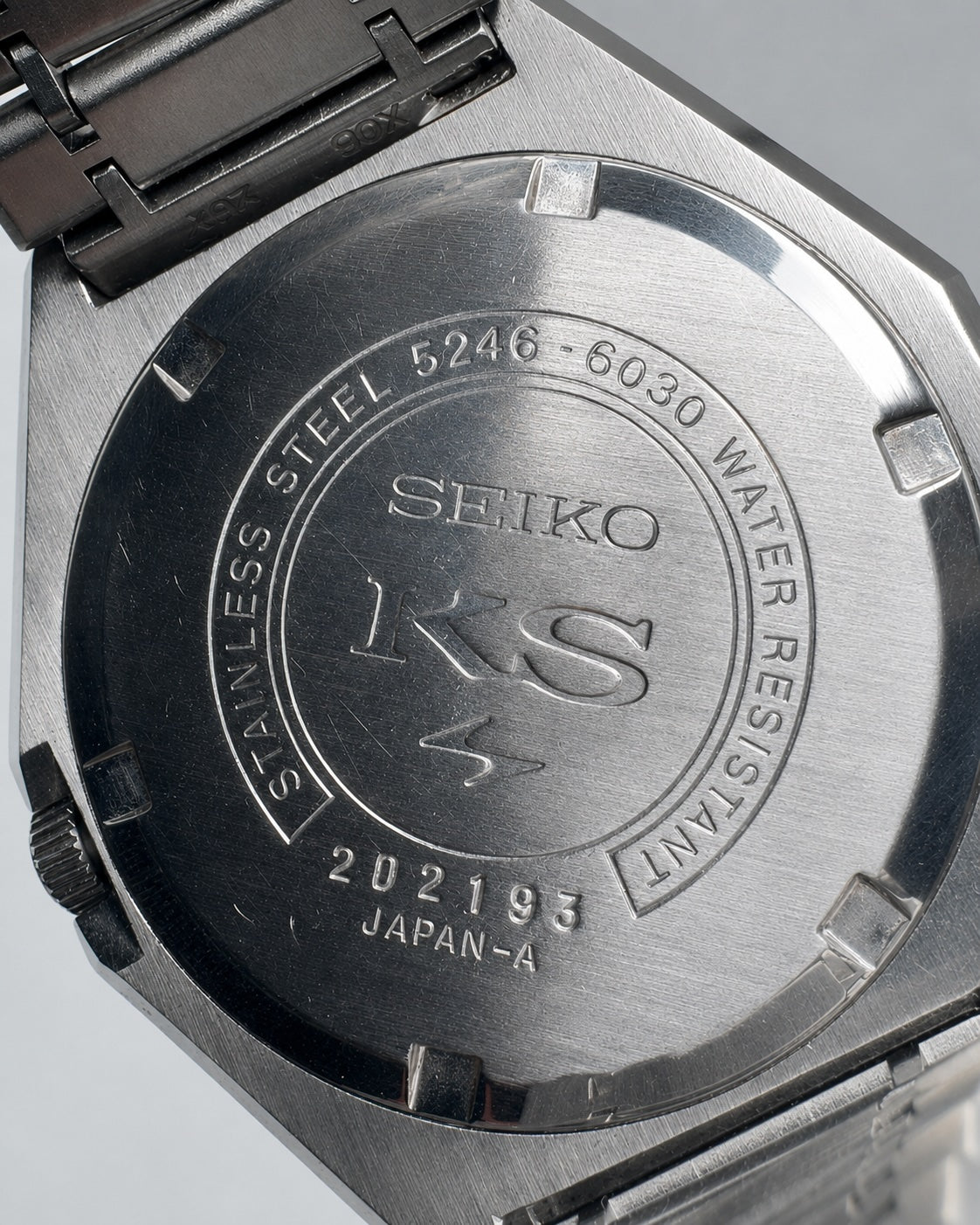 Close-up of the back case of a Seiko stainless steel watch, showing engraved text and the Seiko KS logo on a brushed metal surface.